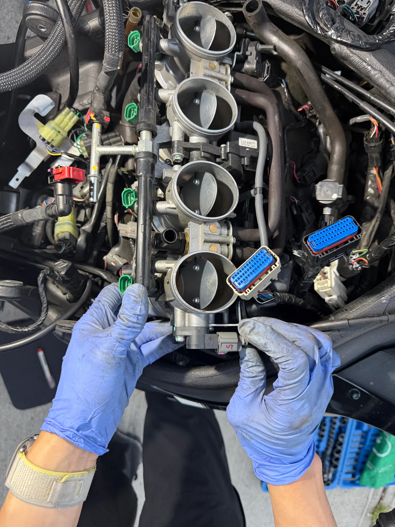 Throttle-body assembly being lifted from a 2011 Kawasaki Ninja ZX-10R during starter motor access